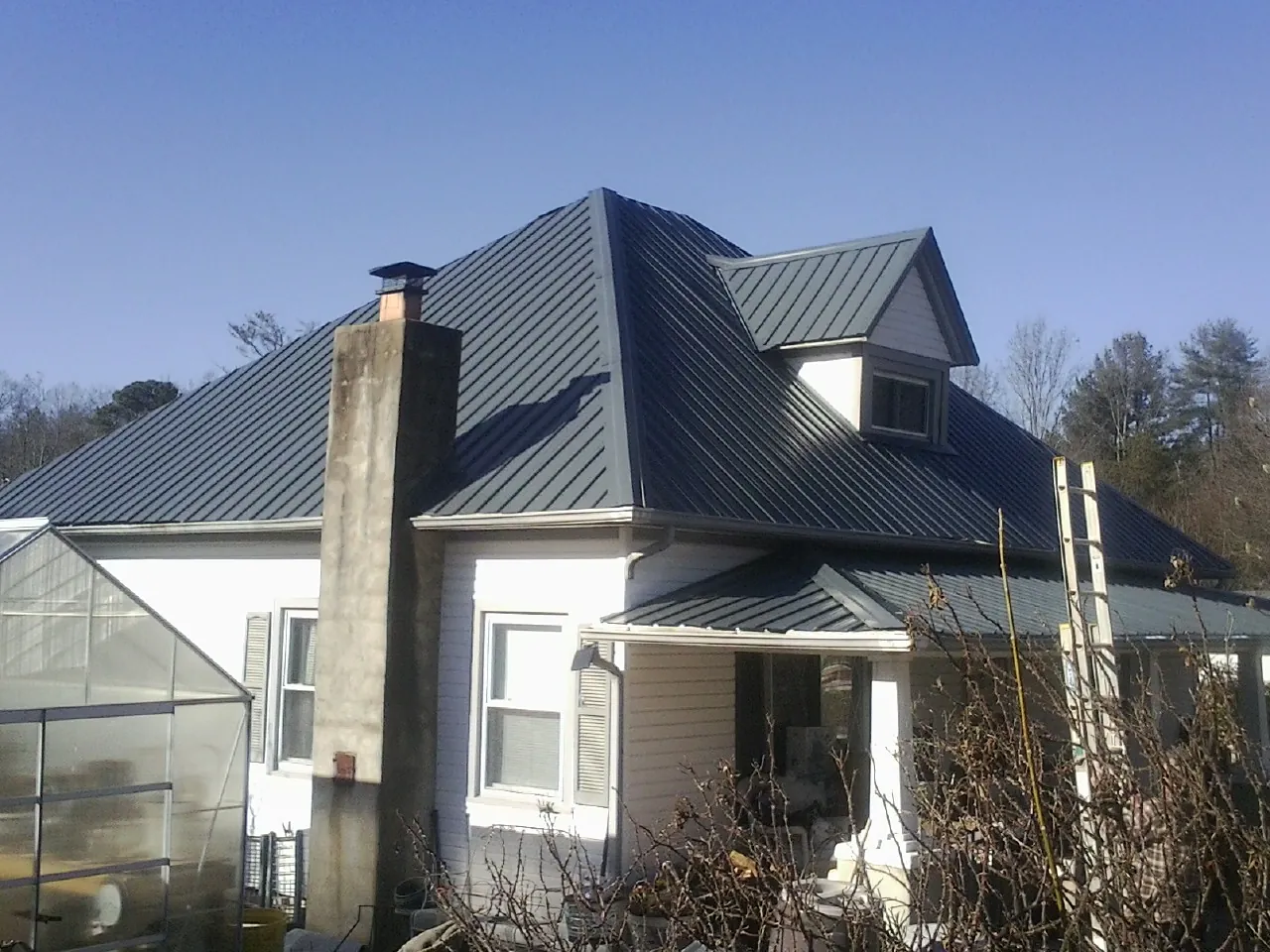 Dark blue standing seam metal roof on a white farmhouse with dormer — Slate & Tile Roof Repair by Roofing Brothers in Samaria