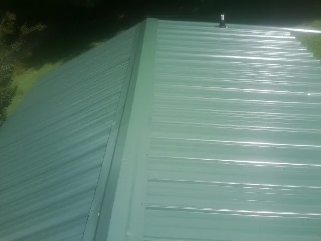 New green metal panels meeting at the ridge of a roof — Flat Roof Repair work by our crew in Samaria