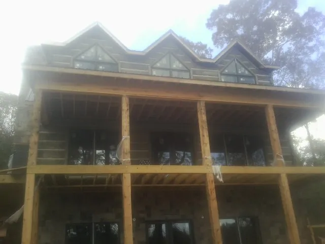 Dormers and porch framing on a large log home under construction — Roof Coating work by our crew in Samaria