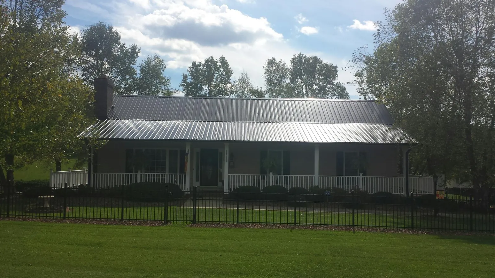 Gray metal roof on a brick ranch with a full width front porch — Gutter Guard Installation work by our crew in Samaria