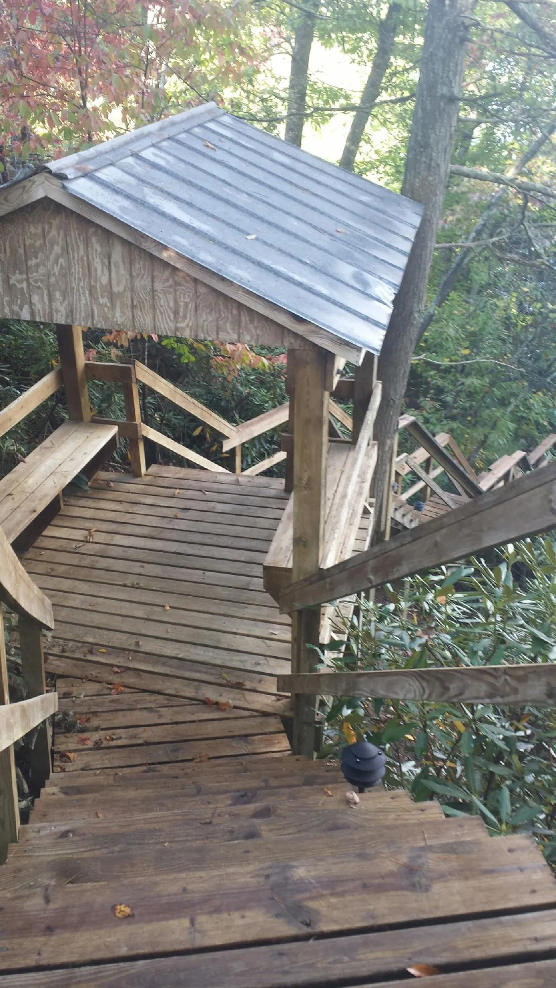 Metal roofed shelter over wooden steps on a wooded walkway — Skylight Repair & Installation work by our crew in Samaria