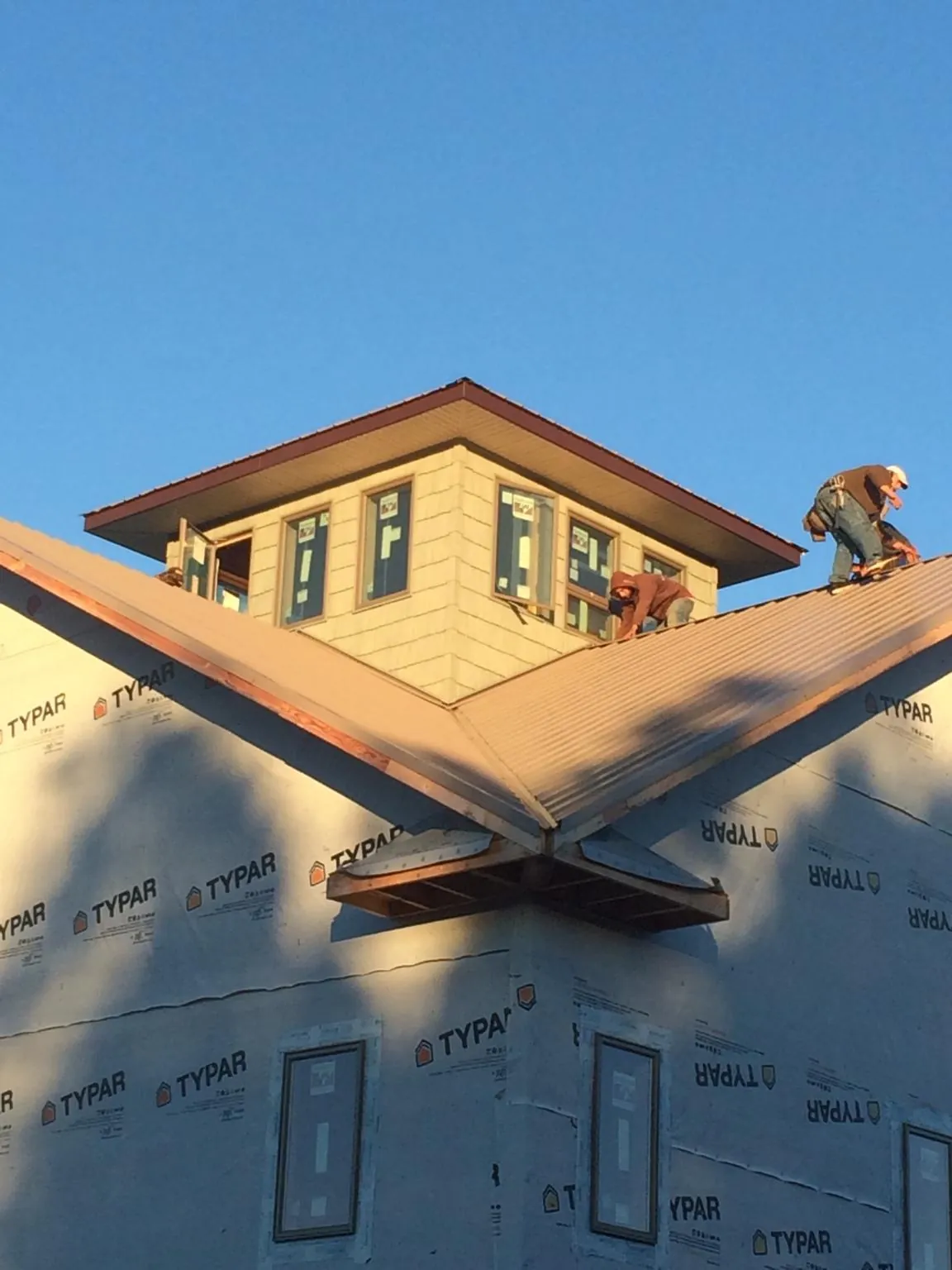 Roofers working around a rooftop cupola on a new metal roof at sunset — Roof Waterproofing in Samaria by Roofing Brothers